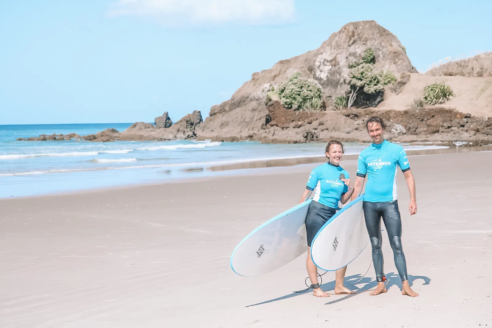 Family carrying surfboards along the beach together
