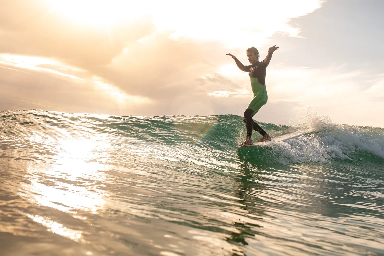 Surfer silhouetted on a golden hour wave